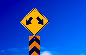 a double arrow traffic sign with a blue sky behind a double arrow traffic sign with a blue sky behind