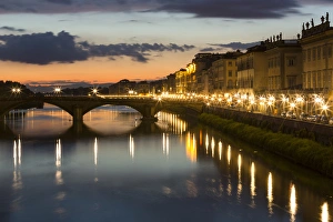 Europe, Italy, Florence. As dusk falls, city streetlights illuminate the riverfront streets Europe, Italy, Florence. As dusk falls, city streetlights illuminate the riverfront streets