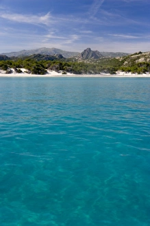 France, Corsica. Clear water and white sand at Saleccio Beach below rugged terrain of DA France, Corsica. Clear water and white sand at Saleccio Beach below rugged terrain of DA