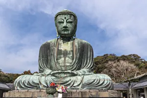 The Great Buddha, Daibutsu, offerings in front, blue sky above in Kamakura, Japan The Great Buddha, Daibutsu, offerings in front, blue sky above in Kamakura, Japan