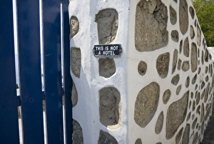 Greece, Mykonos. Gate and stone wall with caution notice for tourists, This is not a hotel Greece, Mykonos. Gate and stone wall with caution notice for tourists, This is not a hotel