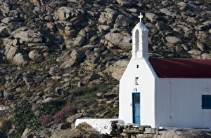 Greece, Mykonos. Sunlit face of church with rocky hill in background Greece, Mykonos. Sunlit face of church with rocky hill in background