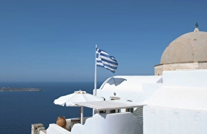 Greek flag flying on porch of white home on steep clifees of Fira in Santorini in Greek flag flying on porch of white home on steep clifees of Fira in Santorini in