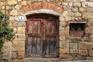 Italy, Monteriggioni. Stone wall, wooden door with planted geraniums Italy, Monteriggioni. Stone wall, wooden door with planted geraniums