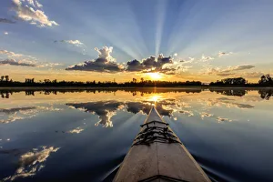 Kayaking into sunset rays on McWennger Slough near Kalispell, Montana, USA Kayaking into sunset rays on McWennger Slough near Kalispell, Montana, USA