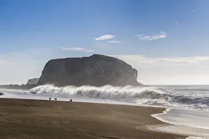 Large haystack rock with crashing waves and birds on the beach in California Large haystack rock with crashing waves and birds on the beach in California