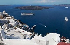 Looking down at white houses and the sea with ships at harbor in Santorini Greece Looking down at white houses and the sea with ships at harbor in Santorini Greece