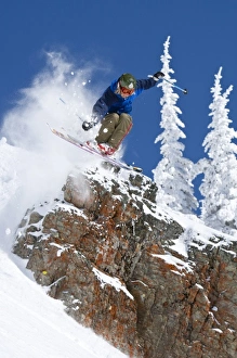 Man jumping colorful cliff and skiing in fresh powder at Whitefish Mountain Resort in Montana Man jumping colorful cliff and skiing in fresh powder at Whitefish Mountain Resort in Montana