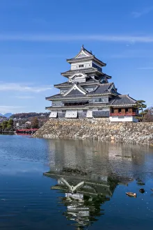 The Matsumoto Castle as seen from the bridge with the city buildings in the background The Matsumoto Castle as seen from the bridge with the city buildings in the background