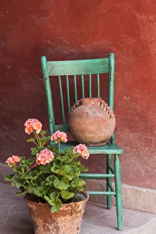 Mexico, San Miguel de Allende. Geraniums, flowerpots and chair decorate an entrance Mexico, San Miguel de Allende. Geraniums, flowerpots and chair decorate an entrance