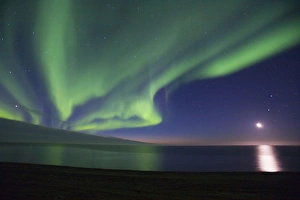 The moon shines down on the Arctic Ocean as curtains of green Aurora Borealis dance The moon shines down on the Arctic Ocean as curtains of green Aurora Borealis dance