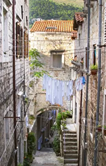 A narrow street leading down with steep steps, clothes lines hanging across the street A narrow street leading down with steep steps, clothes lines hanging across the street