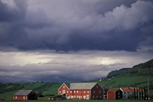 Norway, Orkanger, Trondheim area. Red farm buildings and storm coulds Norway, Orkanger, Trondheim area. Red farm buildings and storm coulds