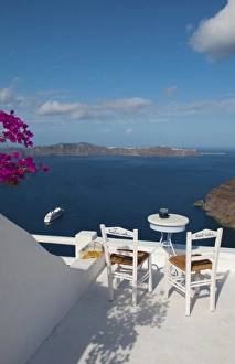 Postcard scene of two lonely chairs on terrace with table ready for tourists in Santorini Postcard scene of two lonely chairs on terrace with table ready for tourists in Santorini