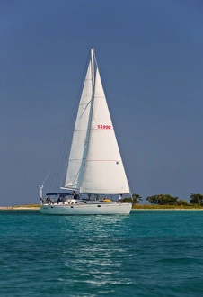 A sail boat sailing by Laughing Bird Cay in Belize A sail boat sailing by Laughing Bird Cay in Belize