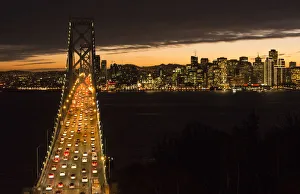 San Francisco California skyline and the Oakland Bay Bridge at evening with traffic on bridge San Francisco California skyline and the Oakland Bay Bridge at evening with traffic on bridge