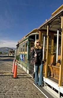 Images Dated 26th December 2007: San Francisco pretty blond female in sunglasses holding on to cable car at Friedel