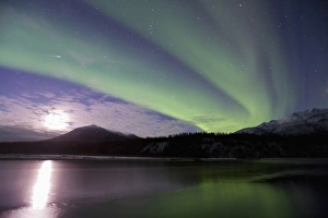 A shooting star cuts through curtains of green aurora borealis dancing over the A shooting star cuts through curtains of green aurora borealis dancing over the