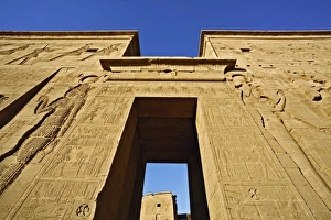 Skyward view of entry pylons and giant figures, Temple of Philae, on Agilika, an Skyward view of entry pylons and giant figures, Temple of Philae, on Agilika, an