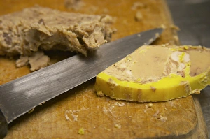 A slice of duck liver foie gras ond a cutting knife on a wooden cutting board Ferme de A slice of duck liver foie gras ond a cutting knife on a wooden cutting board Ferme de