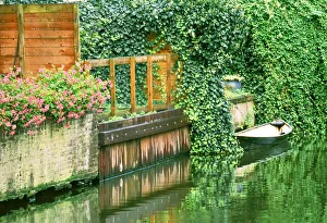 Small boat tied up in a canal next to a garden in Amsterdam Small boat tied up in a canal next to a garden in Amsterdam