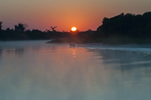 South America, The Pantanal, Brazil, A lone boat at sunrise driving through the rising South America, The Pantanal, Brazil, A lone boat at sunrise driving through the rising