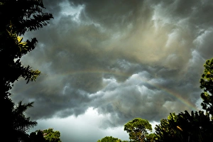 Storm clouds approach in this photograph while a rainbow is illuminated by sunrays Storm clouds approach in this photograph while a rainbow is illuminated by sunrays