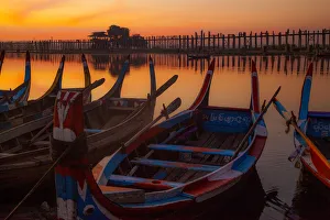 Sunrise over the lake with fishermen on boats fishing in the lake near wooden footbridge Sunrise over the lake with fishermen on boats fishing in the lake near wooden footbridge