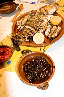 Tangier Morocco clay dishes holding olives, peppers and whole fish in fish restaurant Tangier Morocco clay dishes holding olives, peppers and whole fish in fish restaurant