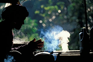 Thailand, Doi Inthanon National Park, Young woman sits by steaming tea kettle at Thailand, Doi Inthanon National Park, Young woman sits by steaming tea kettle at