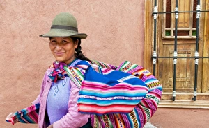 Traditional woman in dress and hat with baby on back in small town of Pisaq Peru Traditional woman in dress and hat with baby on back in small town of Pisaq Peru