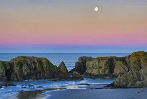 USA, Oregon, Bandon. Full moon sets over sea stacks on beach USA, Oregon, Bandon. Full moon sets over sea stacks on beach