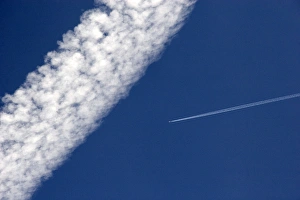 Vapor contrails from high flying jet aircraft. The larger has been blown apart by Vapor contrails from high flying jet aircraft. The larger has been blown apart by