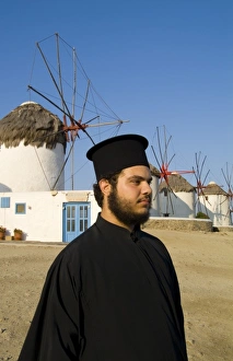 White and blue windmills with a Greek Orthodox priest on the island of Mykonos, Greece White and blue windmills with a Greek Orthodox priest on the island of Mykonos, Greece