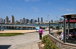Woman walking on pavement with scenic of skyline of San Diego from Coronado Island Woman walking on pavement with scenic of skyline of San Diego from Coronado Island
