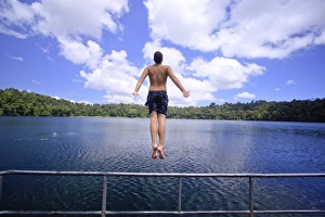 A young man jumps into the refreshing waters of Lake Eacham in the Crater Lakes National Park A young man jumps into the refreshing waters of Lake Eacham in the Crater Lakes National Park