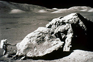 APOLLO 17: BOULDER, 1972. Astronaut Harrison H. Jack Schmitt standing by a huge split boulder on the surface of APOLLO 17: BOULDER, 1972. Astronaut Harrison H. Jack Schmitt standing by a huge split boulder on the surface of