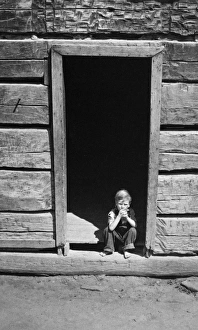 LOG CABIN, 1940. Child in doorway of an old mountain cabin made of hand-hewn logs LOG CABIN, 1940. Child in doorway of an old mountain cabin made of hand-hewn logs