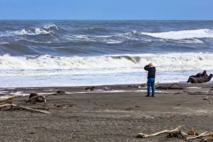 A photographer photographing the waves on the beach at Hokitika in West Coast A photographer photographing the waves on the beach at Hokitika in West Coast