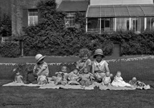 Three girls in a garden with dolls