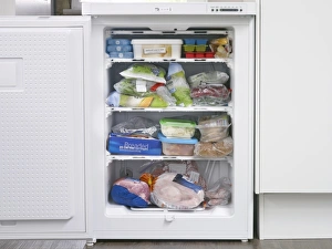 Frozen food in full freezer with open door Frozen food in full freezer with open door