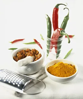 Ground turmeric, crushed spices in mortar, and whole green and red chilli peppers in glass Ground turmeric, crushed spices in mortar, and whole green and red chilli peppers in glass