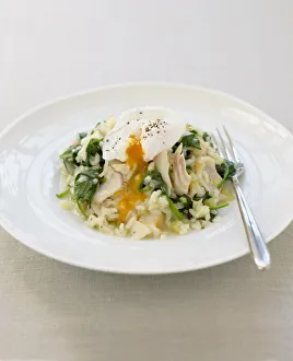 Haddock risotto with spinach and poached egg on a plate, with a fork Haddock risotto with spinach and poached egg on a plate, with a fork