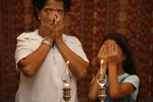 Mother and daughter lighting Shabbat candles and praying Mother and daughter lighting Shabbat candles and praying