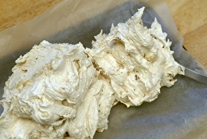Placing a nougat sweet mixture into a tin lined with greaseproof paper Placing a nougat sweet mixture into a tin lined with greaseproof paper