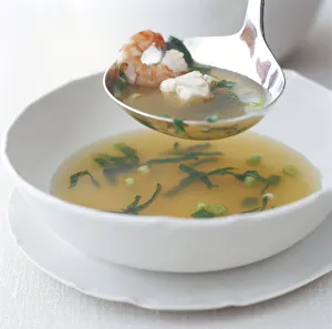 Prawn and sea bass clear soup on a ladle and in bowl below Prawn and sea bass clear soup on a ladle and in bowl below