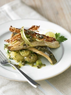Sea bass served on plate with new potatoes, and capers on top Sea bass served on plate with new potatoes, and capers on top