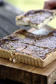 Serving slice of gruyere tart defocused from whole tart cut into squares Serving slice of gruyere tart defocused from whole tart cut into squares