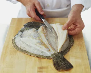 Using a knife to cut fillets off a raw turbot Using a knife to cut fillets off a raw turbot