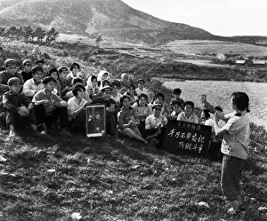 During a work break, a young woman is leading the commune workers in singing a song During a work break, a young woman is leading the commune workers in singing a song